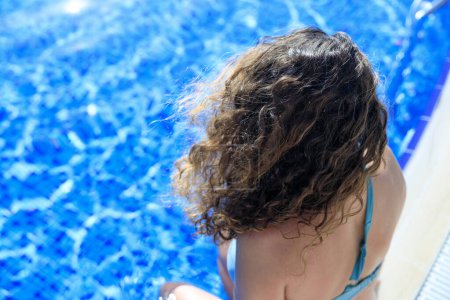 Photo for Top shot of woman sunbathing with messy hair by the pool - Royalty Free Image