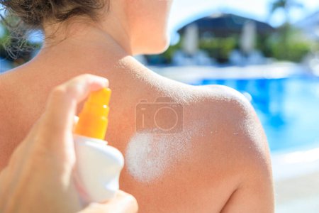 Photo for Man's hand is applying sunblock on woman's shoulde - Royalty Free Image