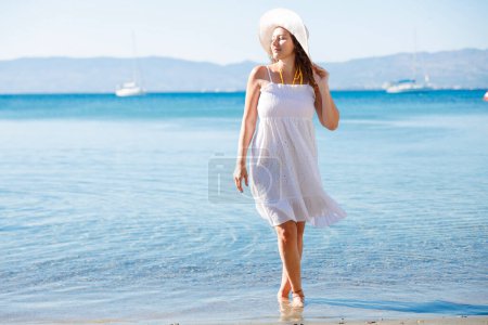 Téléchargez les photos : Femme heureuse en robe blanche bénéficie de vacances à la plage tropicale - en image libre de droit
