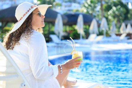 Téléchargez les photos : Heureuse jeune femme profitant d'une journée d'été ensoleillée à la piscine extérieure - en image libre de droit