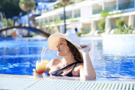 Téléchargez les photos : Heureuse jeune femme profitant d'une journée d'été ensoleillée à la piscine extérieure - en image libre de droit