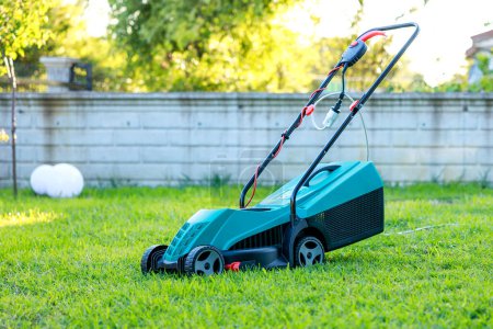 Photo for Lawn mower on green grass in back yard - Royalty Free Image