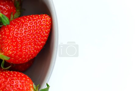 Foto de Tiro extremadamente macro de fresas en un tazón y gran espacio de copia sobre fondo blanco aislado - Imagen libre de derechos