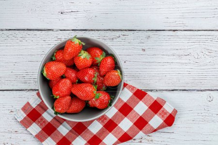 Téléchargez les photos : Délicieuses fraises fraîches dans un bol sur fond de bois blanc - en image libre de droit
