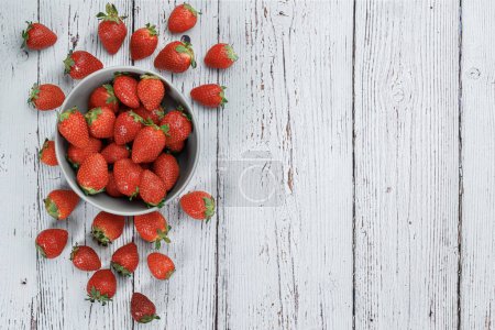 Photo for Delicious fresh strawberries in a bowl on white wooden background - Royalty Free Image