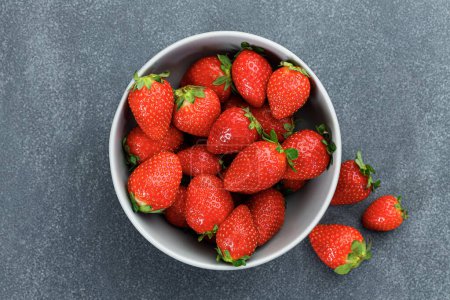 Téléchargez les photos : Délicieuses fraises fraîches dans un bol sur fond de marbre - en image libre de droit