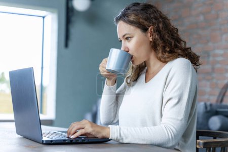Photo for Morning routine of young freelancer woman checking her mail while drinking coffee - Royalty Free Image