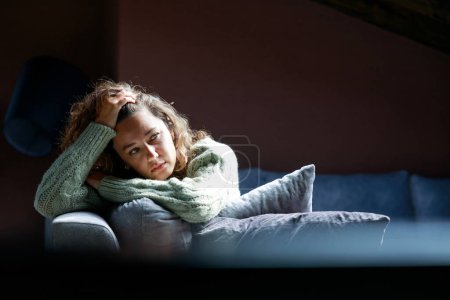 Photo for Young woman lying at home in living room sitting on sofa. She feeling sad and worried suffering depression in mental health. Problems and broken heart concept - Royalty Free Image