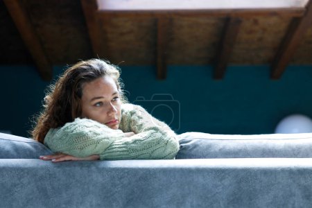 Téléchargez les photos : Jeune femme allongée à la maison dans le salon assis sur le canapé. Elle se sent triste et inquiète de souffrir de dépression en santé mentale. Problèmes et concept du cœur brisé - en image libre de droit
