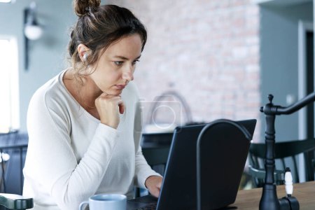 Foto de Freelancer enfocado mujer joven mirando el ordenador portátil - Imagen libre de derechos