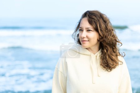 Téléchargez les photos : Jeune femme jouissant du calme au bord de la mer seule en automne - en image libre de droit