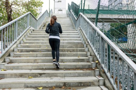 Téléchargez les photos : Jeune athlète féminine montant les escaliers du centre-ville - en image libre de droit