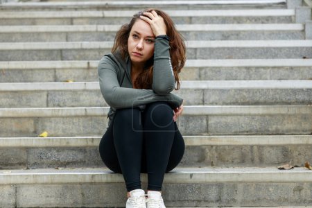 Foto de Mujer decepcionada y triste sentada en las escaleras. Ella se sienta sola y piensa en un triste y deprimido en las escaleras - Imagen libre de derechos