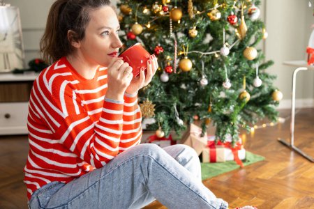 Foto de Mujer joven bebiendo café por la Navidad tre - Imagen libre de derechos