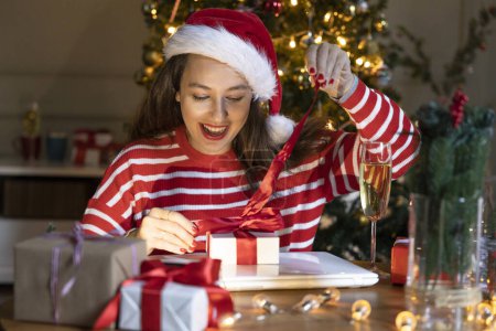 Photo for Young woman opening her presents on Christmas night - Royalty Free Image