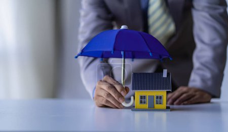 a businessman spreading a blue umbrella for the house Real estate, insurance and property concepts