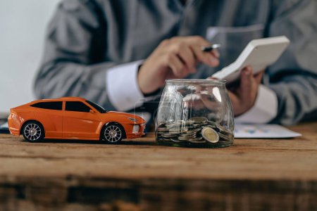 Toy car and coins on table, saving money concept to spend car expenses and growing business