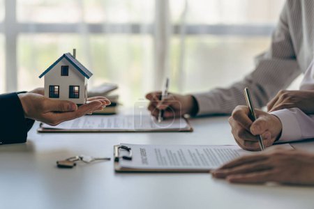 Immobilienmakler verhandeln über die Konditionen der Zinsvereinbarung für den Ratenkauf eines Eigenheims. und bitten Kunden, einen Vertrag zu unterzeichnen