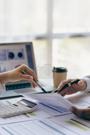 Foto per Team of business people holding pen pointing to bar chart at company financial papers meeting, group of business people together concept vertical image - Immagine Royalty Free