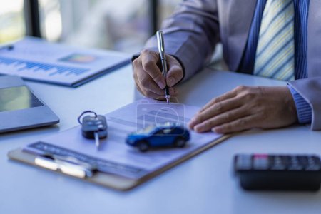 Foto de A car dealer or sales manager offers to sell a car and explains the terms of signing a car and insurance contract. - Imagen libre de derechos