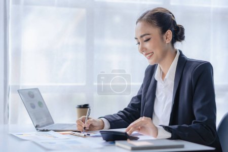 Téléchargez les photos : Concept de système financier et fiscal, belle femme d'affaires asiatique souriante travaillant sur ordinateur portable Faire un rapport d'analyse de compte de données d'investissement immobilier - en image libre de droit