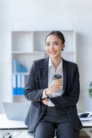 Téléchargez les photos : Concept de système financier et fiscal, belle femme d'affaires asiatique souriante travaillant sur ordinateur portable Faire un rapport d'analyse de compte de données d'investissement immobilier - en image libre de droit
