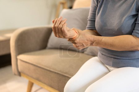 Photo for Elderly female patient suffers from inflammatory wrist pain, beriberi or peripheral neuropathy, elderly woman massaging hands with wrist pain - Royalty Free Image