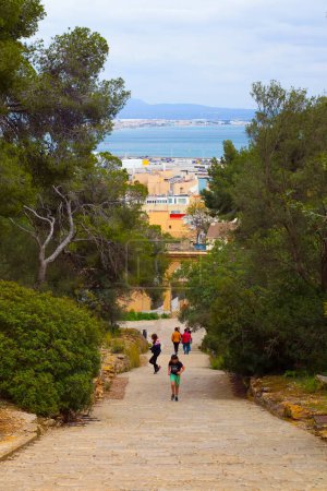Foto de Palma de Mallorca, España, 4 de abril de 2022 - Niño subiendo escaleras con árboles y mar detrás - Imagen libre de derechos