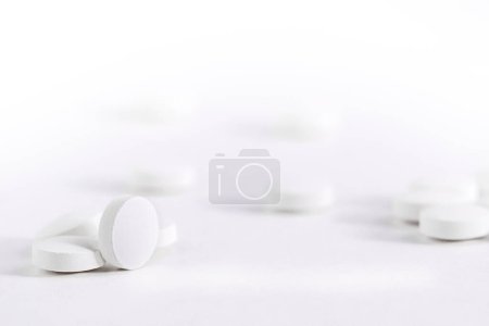 Téléchargez les photos : Bulk pilules blanches reposent sur une table blanche, Vue de face vierge pour l'espace de copie de conception. - en image libre de droit