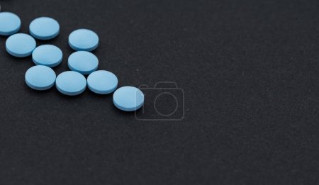 Photo for Heap of blue pills on a black table. - Royalty Free Image
