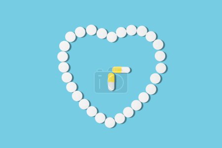 Téléchargez les photos : Pilules médicales en forme de cœur sur fond bleu et deux pilules jaunes, symbolisant le cycle de la prise de médicaments. - en image libre de droit