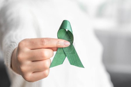 Woman holding green ribbon for cancer awareness month. Healthcare and world cancer day concept