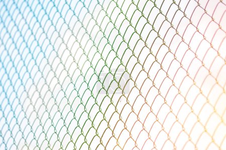 Mesh fence or metal grid at sunset. Steel grating fence made with wire on blue sky background