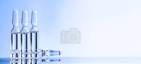 Foto de Cuatro ampollas sobre el escritorio sobre fondo azul. Concepto de medicina. - Imagen libre de derechos