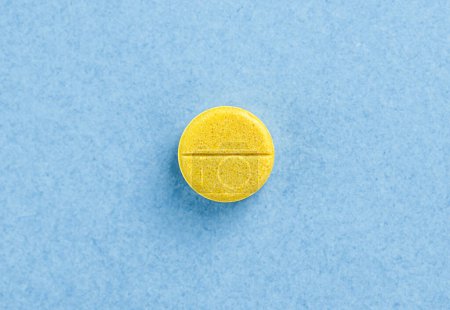 Single yellow pill tablet. Tablet on blue background with copy space. Health concept
