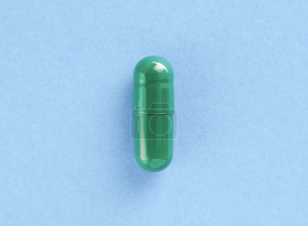 Green two-piece hard starch capsule on blue background with copy space. Medical and Health concept