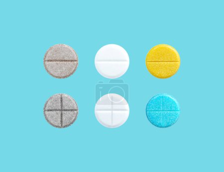 Different colored pills in a row on blue background with copy space. Biologically active additives. Medical and Health concept.