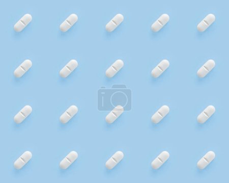Pilules blanches capsules sur fond bleu. Pilules répétitives sans couture.