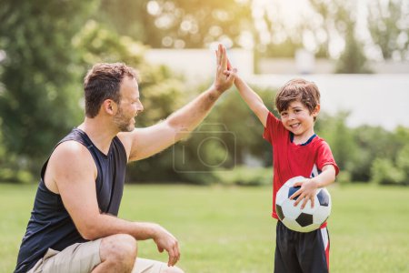 A Young soccer player having fun on a field with his father