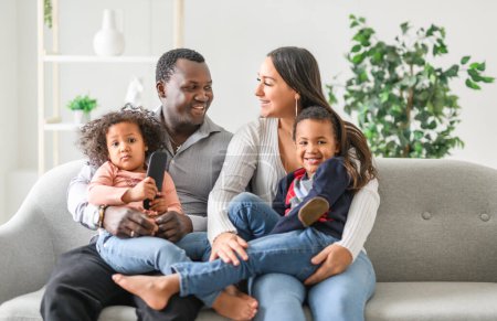 A family with boy and girl child posing on photo shooting, sitting on couch