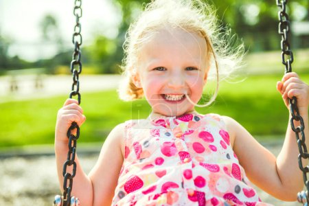 Ein glückliches 3-jähriges Mädchen auf einer Schaukel. Glückliches Kind auf dem Spielplatz