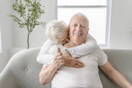 A senior retired couple having great moment together on cozy sofa in living room.