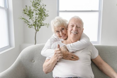 Ein Rentnerehepaar hat einen schönen Moment zusammen auf dem gemütlichen Sofa im Wohnzimmer.