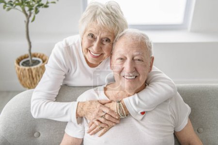 A senior retired couple having great moment together on cozy sofa in living room.