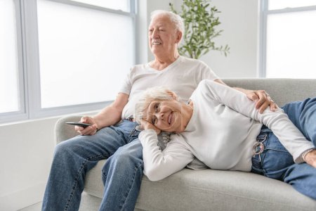 Ein Rentnerehepaar hat einen schönen Moment zusammen auf dem gemütlichen Sofa im Wohnzimmer.