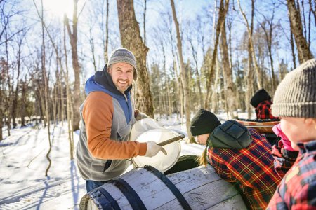 A sugar shack, a maple farmer wearing a traditional clothe working take maple water