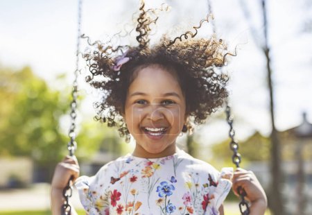 Una chica feliz de 4 años en un columpio. Niño feliz en el patio