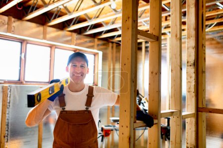 Un obrero de la construcción usando una herramienta eléctrica en el sótano inacabado de un nuevo hogar