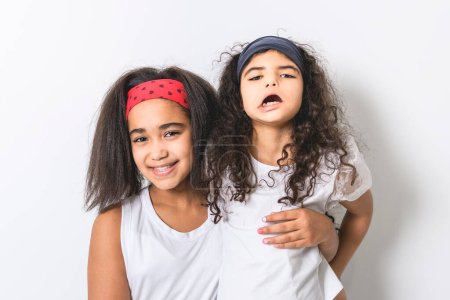 Ein entzückendes 9-jähriges Mädchen auf weißem Studiohintergrund mit ihrer Schwester