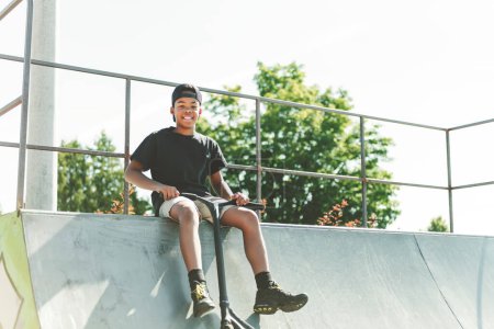 Ein afroamerikanischer Junge mit schwarzem T-Shirt posiert auf einem Skatepark